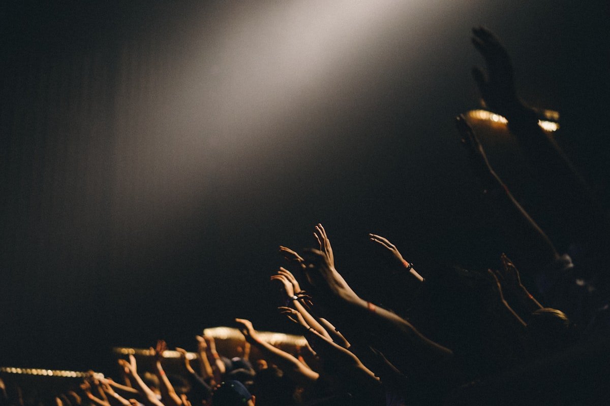 Hands raised in prayer, lit by a single shaft of light