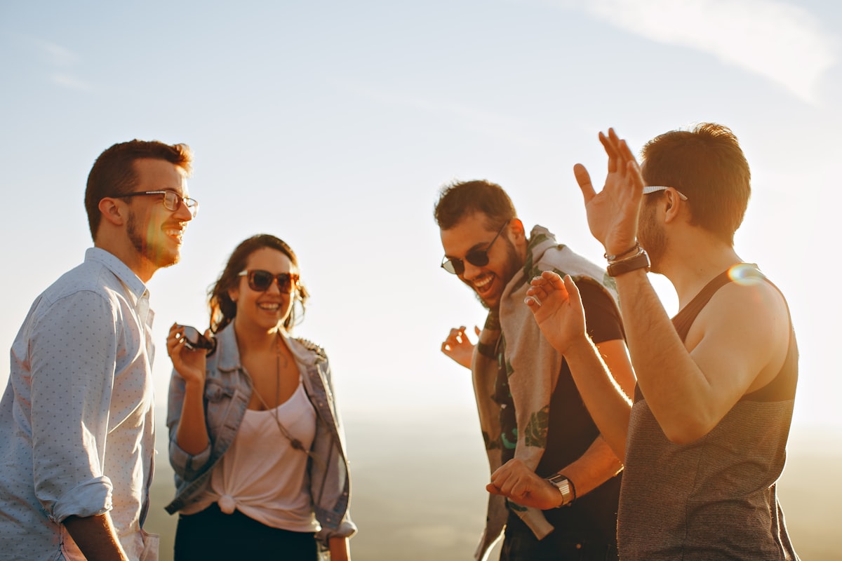 Friends welcoming one another with laughter at sunset