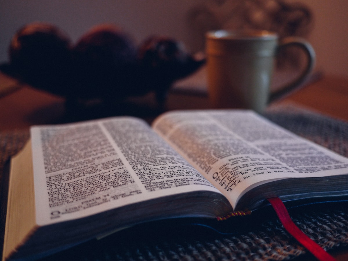 An open Bible beside a warm cup in the quiet of early morning