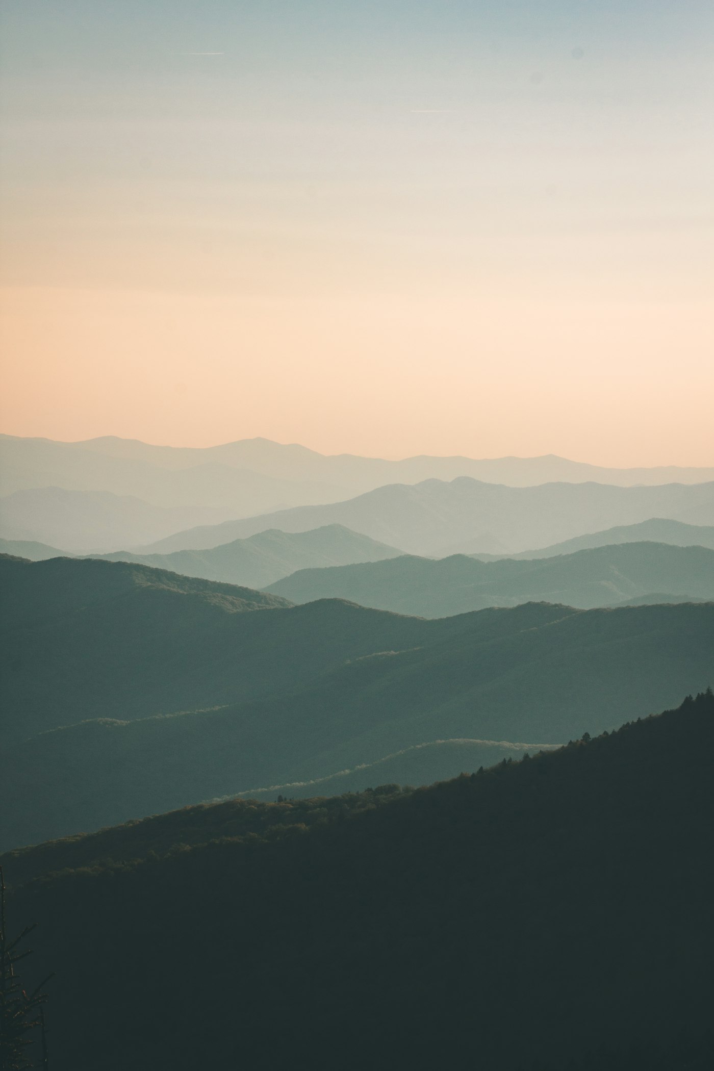Layered mountain ridges softening into mist at first light