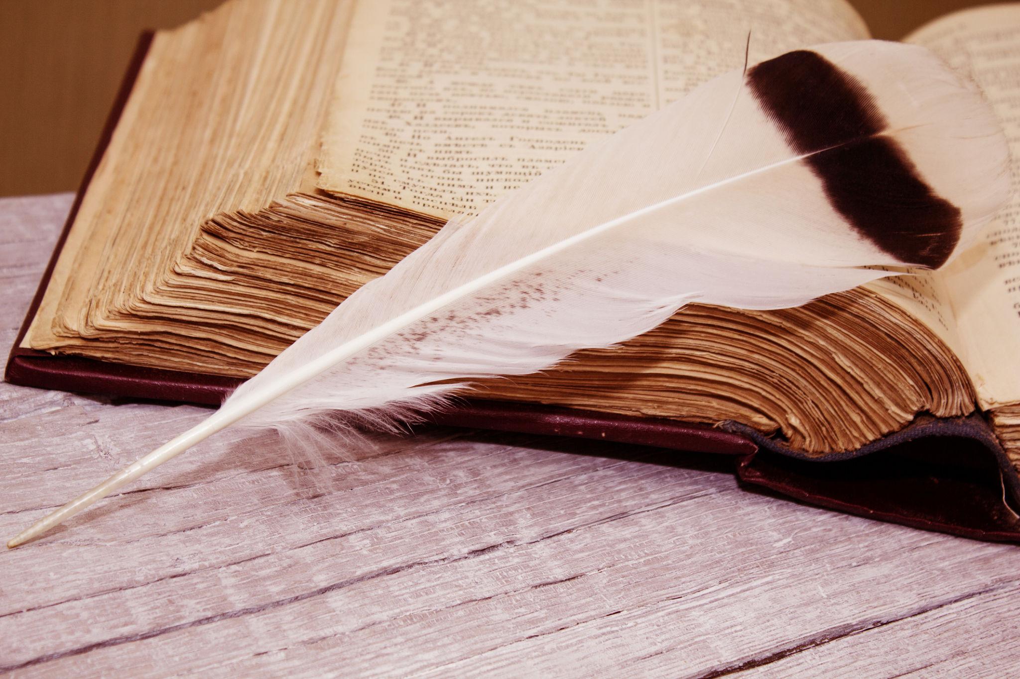 Old book with a quill feather